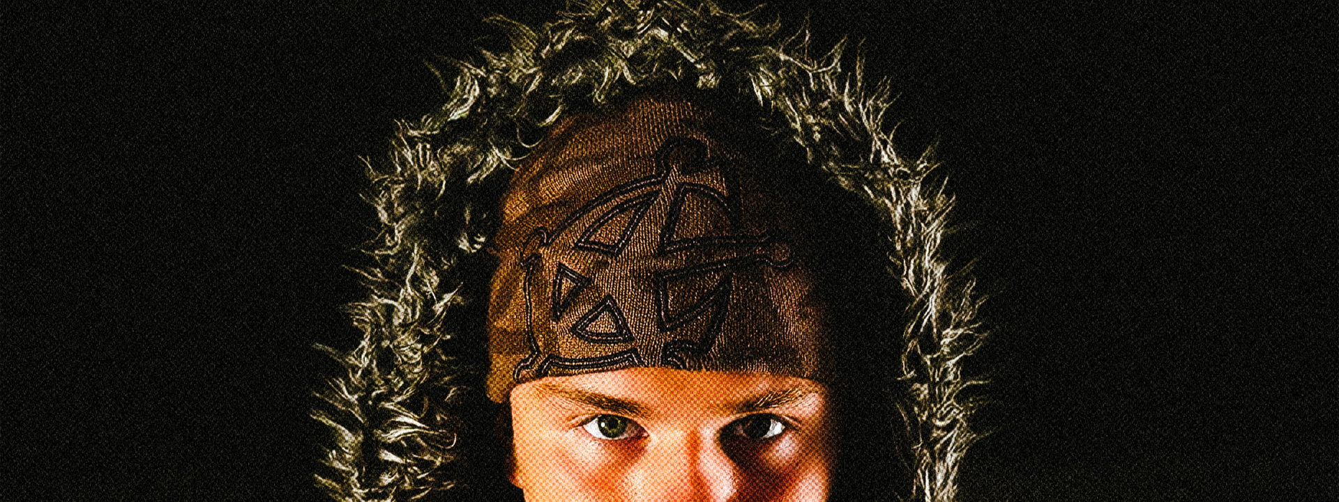 Person wearing a hooded jacket and beanie with a dark background